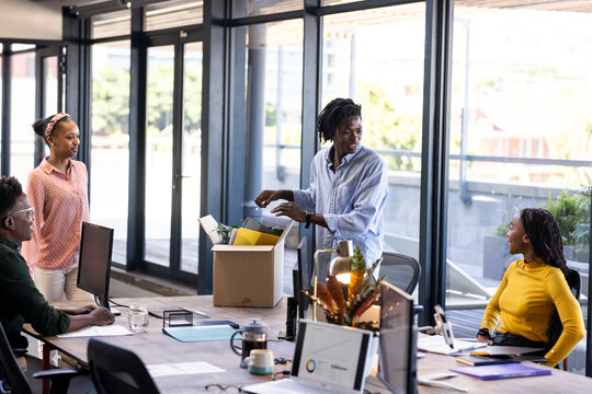African American team collaborating in modern office, unpacking box with enthusiasm