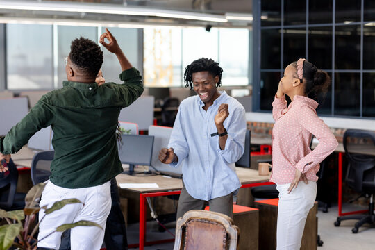 In office, colleagues celebrating successful project, dancing joyfully together