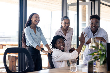 Team celebrating success in modern office, smiling and high-fiving around desk