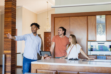 Showing modern kitchen, real estate agent discussing home features with couple