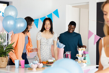 Friends celebrating at home, enjoying snacks and drinks with colorful decorations