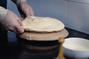 Dough for Uzbek flatbread is rolled out on table