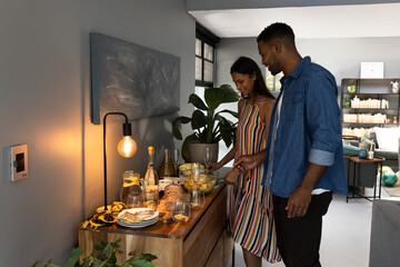 Couple preparing snacks and drinks at home for evening celebration