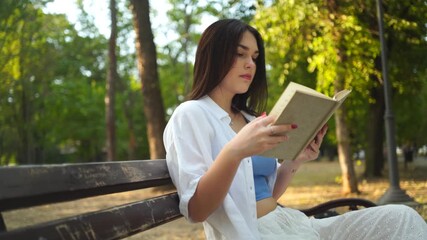 A young and beautiful woman reading a book in the park - Powered by Adobe