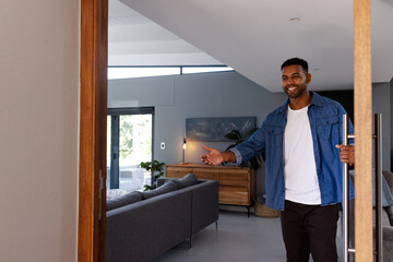 Man welcoming guests into modern living room, smiling and extending hand warmly