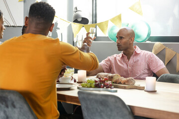 Friends toasting with drinks at festive table, celebrating together indoors