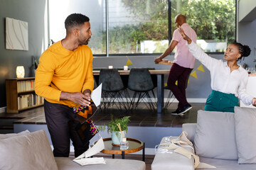 Decorating living room for celebration, African American friends arranging items enthusiastically