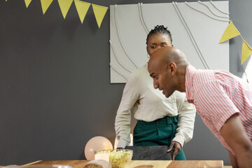 Man and woman preparing for celebration, arranging table with snacks and decorations