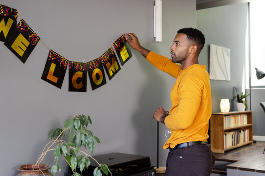 Man hanging welcome banner in living room, preparing for celebration event