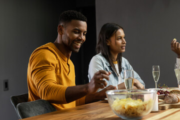 Friends enjoying snacks and drinks at home, smiling and chatting together