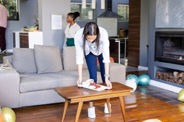 Woman arranging snacks on coffee table at home during festive celebration