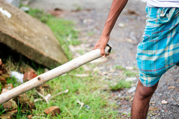 Man holding a wooden tool, possibly for farming or construction work