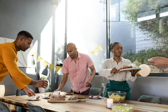 Friends preparing dinner table with decorations, enjoying festive gathering at home
