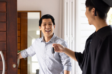 Father welcoming graduate son home, smiling as he receives car keys at door