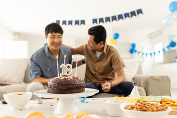 Celebrating 18th birthday, father and son sharing joyful moment at home party