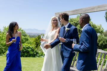 Bride and groom holding hands, celebrating with friends outdoors, enjoying champagne