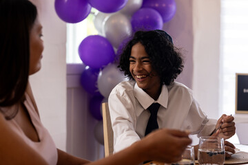 In formal attire, child smiling and talking during bar mitzvah at home