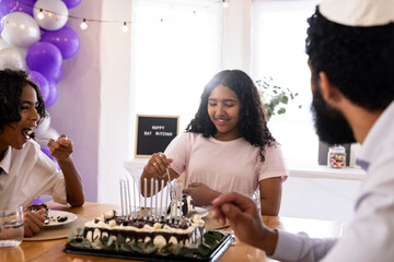 Family celebrating Bat Mitzvah with cake, sharing joyful moments together at home