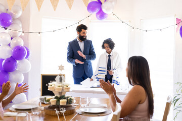 Father and son celebrating Bar Mitzvah with family, clapping and smiling together