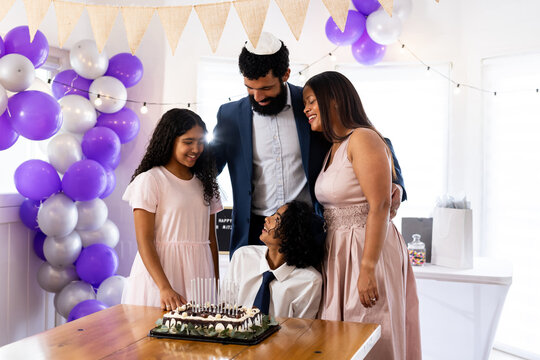 Family celebrating bar mitzvah together with cake and decorations at home - Powered by Adobe
