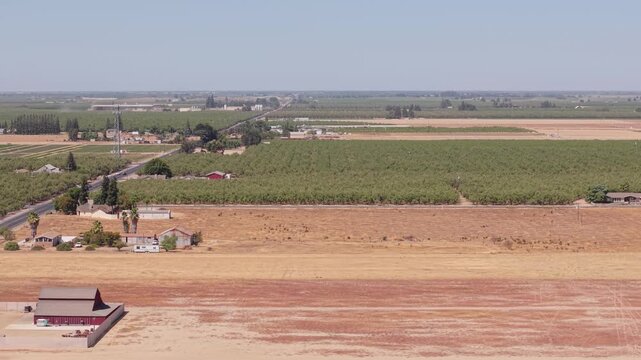 Aerial wide shot showing farmland, houses, and road with traffic in Ripon California.