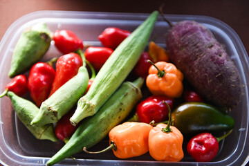 Mixed hot peppers, okra, and purple sweet potato in a bin