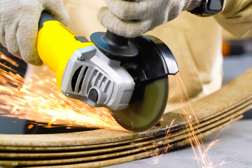 Cutting steel with angle grinder sparks from sawing car leaf springs.