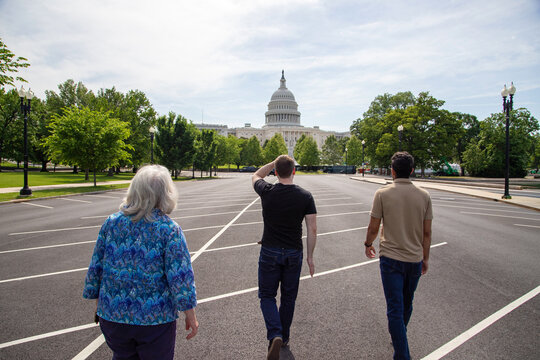 Three people walking towards the US Capitol building