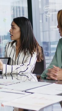 Vertical video: During meeting female colleagues opening laptop and reviewing charts for next topic