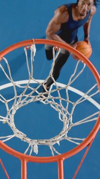 Vertical video: Spotting rim African American man is entering before dunking ball to score on court