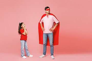 Full body young happy cool parent man child girl wearing red casual clothes super hero coat mask. Daddy little kid daughter isolated on plain pastel pink background Father's Day Love family concept.
