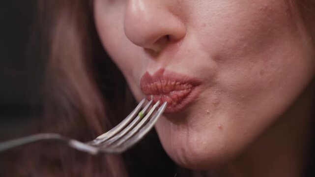 Extreme close up of lady using tongue and mouth to eat creamy waffle from fork, showing detail of lips and dessert texture in intimate food moment during indoor meal