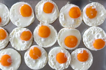 Fried egg arranged in a neat pattern on a baking tray in a bright kitchen setting during the morning hours