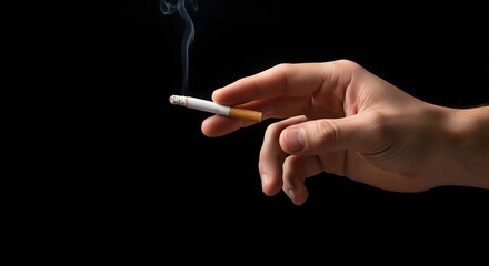 Smoking cigarette in hand on black background concept of nicotine addiction and health risks photo