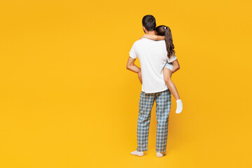 Full body back view young parent man with child girl wear casual blue pyjamas clothes. Daddy hold...
