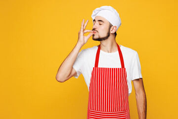 Young housekeeper chef cook baker man he wear red apron toque hat making okay taste delight sign,...