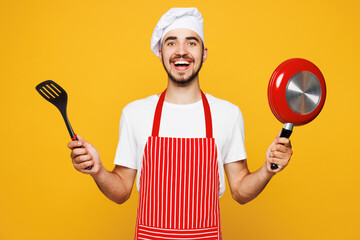 Young smiling happy housewife housekeeper chef cook baker man wear red apron toque hat hold in hand...