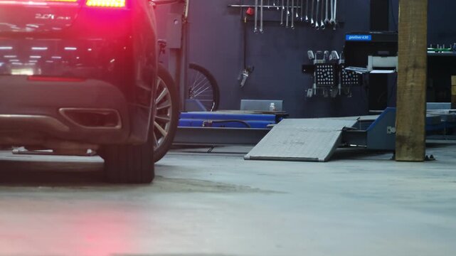 Modern vehicle reverses in spacious hall after repairs. Car leaves special auto service center using bright taillights to signal traffic
