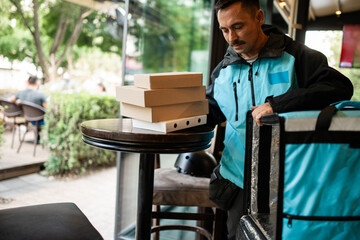 Delivery man arranging pizza boxes on table in restaurant