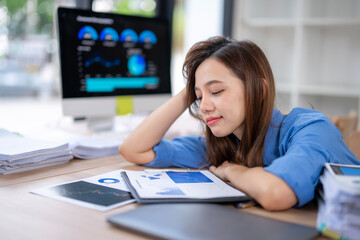 Exhausted businesswoman sleeping on desk at workplace after working hard on financial reports