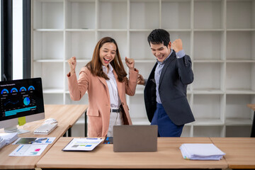 Business people celebrating success looking at laptop in office