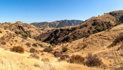 Dry, rolling hills descend into a valley under a clear sky