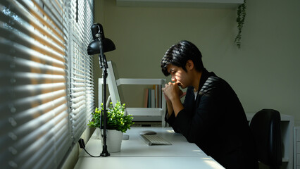 Stressed businessman sitting at desk with head down, feeling pressure from work challenges