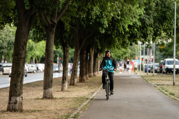 Obraz premium Delivery man riding bicycle in city park delivering food