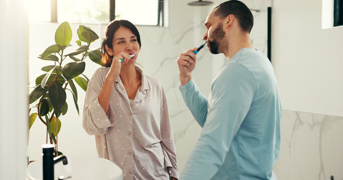 Happy couple, brushing teeth and bathroom with toothbrush for dental hygiene or morning routine. Man, woman or fresh breath with clean mouth for gum, oral care or health and wellness together in home - Powered by Adobe