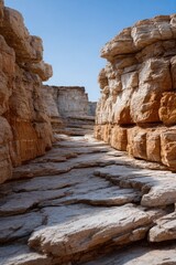 Scenic canyon path with rocky cliffs under clear blue sky.