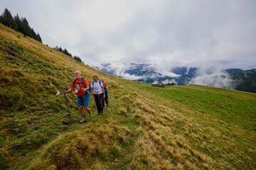 Obraz premium a couple with their grandfather walking in the mountains on a cloudy and foggy day.