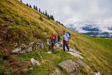 Fototapeta premium a couple with their grandfather walking in the mountains on a cloudy and foggy day.
