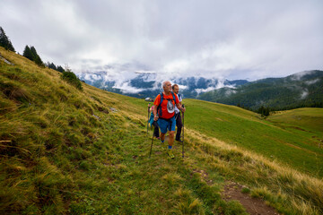Fototapeta premium a couple with their grandfather walking in the mountains on a cloudy and foggy day.