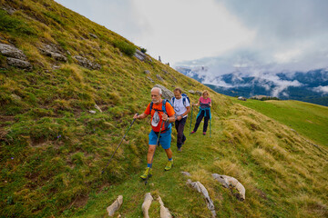 Fototapeta premium a couple with their grandfather walking in the mountains on a cloudy and foggy day.